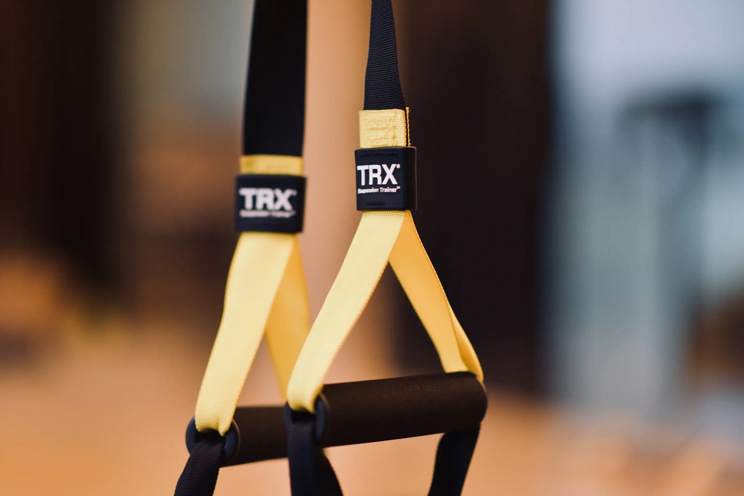 Correas de suspensión TRX amarillas colgando, listas para una sesión al aire libre